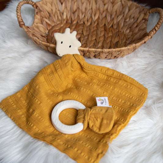 Mustard yellow textured blanket with white rings on a fluffy white surface, with a woven basket in the background.