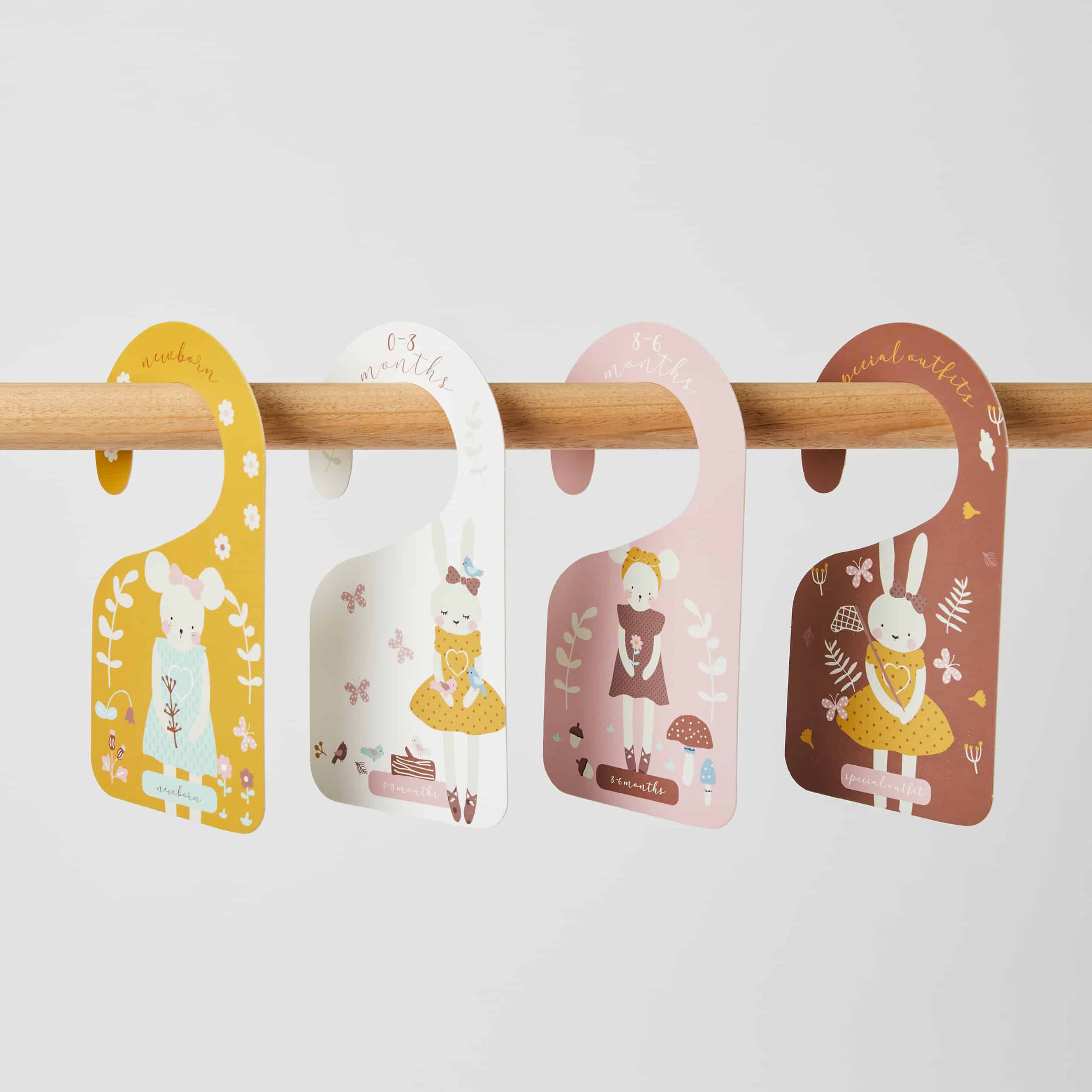 Four colorful children's name tags hanging on a wooden rod against a light gray background.