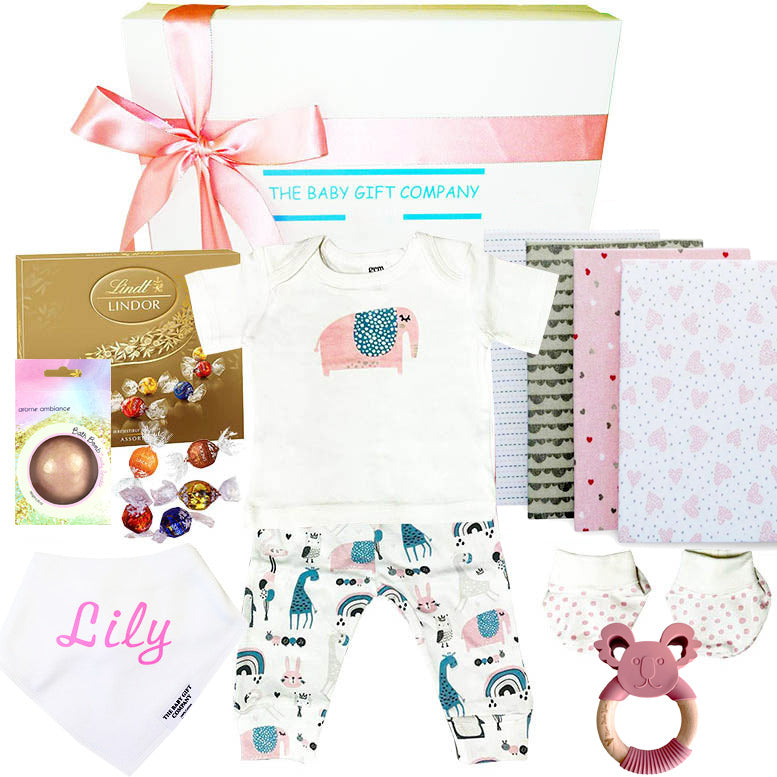 Baby gift set with clothing, toys, and Lindt chocolate on a white background