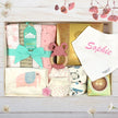 Baby gift set with blankets, a teether, and a bib on a wooden surface.