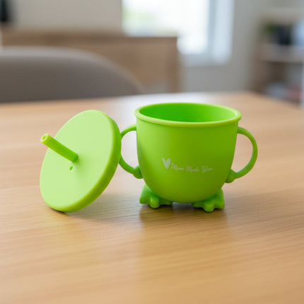 Green sippy cup with lid on a wooden table background