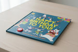 Children's book titled 'Happy Birthday To You!' with colorful illustrations of animals and balloons on a blue background.