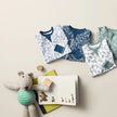Children's clothing with patterned shirts and a toy on a light background