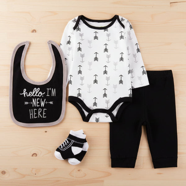 Baby outfit set with bodysuit, bib, pants, and socks on a table background