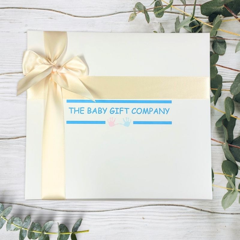 Gift box with a bow on a wooden surface with greenery