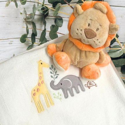 Leo Lion Baby Gift Box with lion soft toy and jungle animal bath towel. Displayed in a gift box and a wooden table