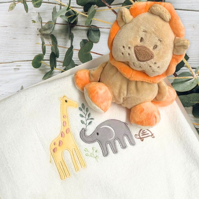 Leo Lion Baby Gift Box with lion soft toy and jungle animal bath towel. Displayed in a gift box and a wooden table