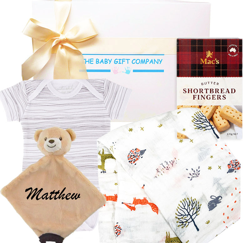 Baby gift set with baby clothes, plush toy, and cookies on a white background