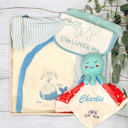 Baby clothing set with a green octopus toy on a wooden surface