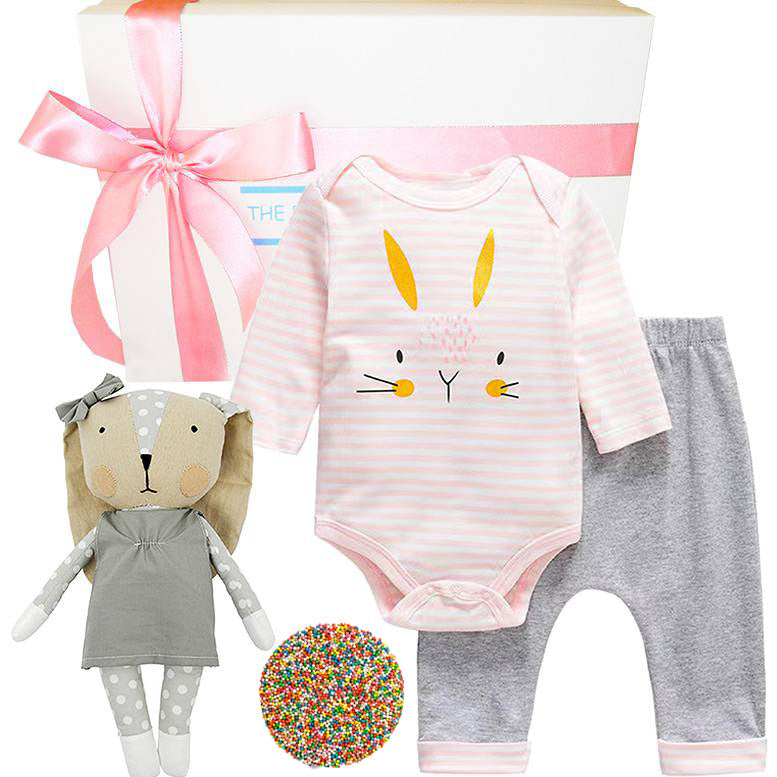 Baby outfit with onesie, pants, and plush toy on a white background