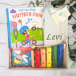 Educational toy set with 'Lift-the-Flap Number Fun' book and colorful wooden toys on a white surface.