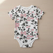 Floral-patterned baby onesie with short sleeves on a table background