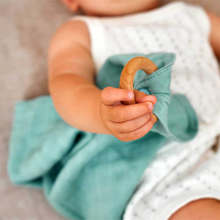 Baby holding a wooden toy with a blurred background