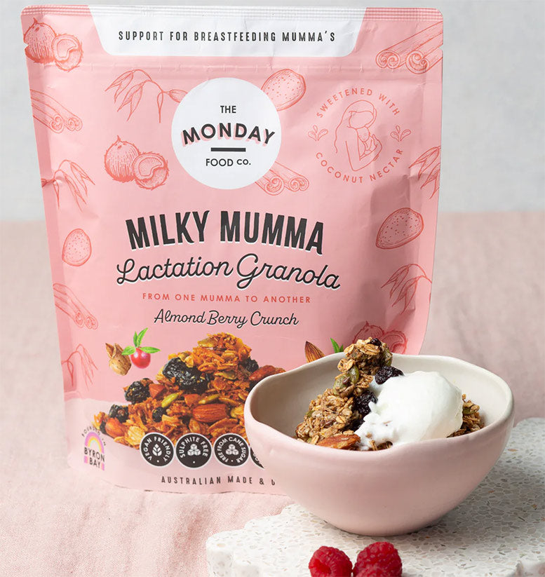 Pink package of 'Milky Mumma Lactation Granola' from The Monday Food Co. with a bowl of granola and berries on a light background.