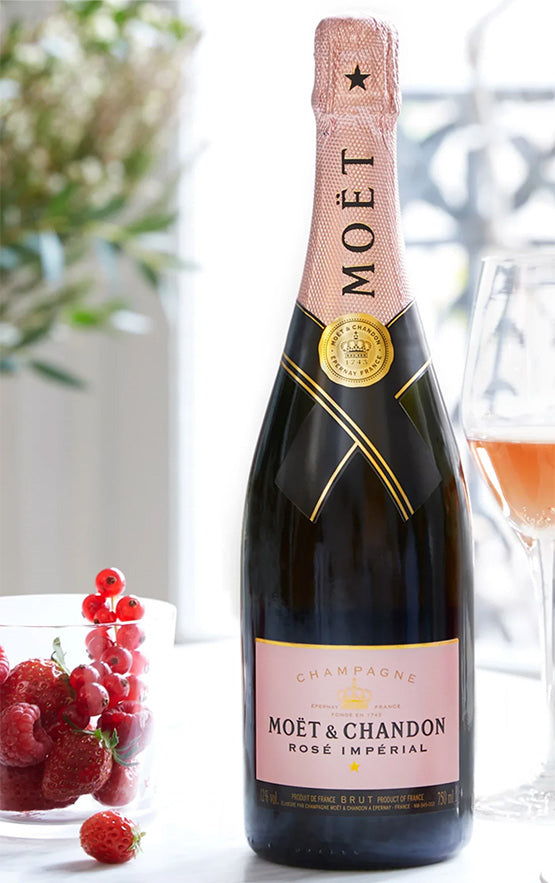 Moét & Chandon Rosé Imperial champagne bottle with a glass of champagne and grapes in the background.