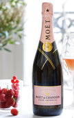Moét & Chandon Rosé Imperial champagne bottle with a glass of champagne and grapes in the background.