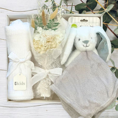 grey bunny, flowers and white blanket within a gift hamper