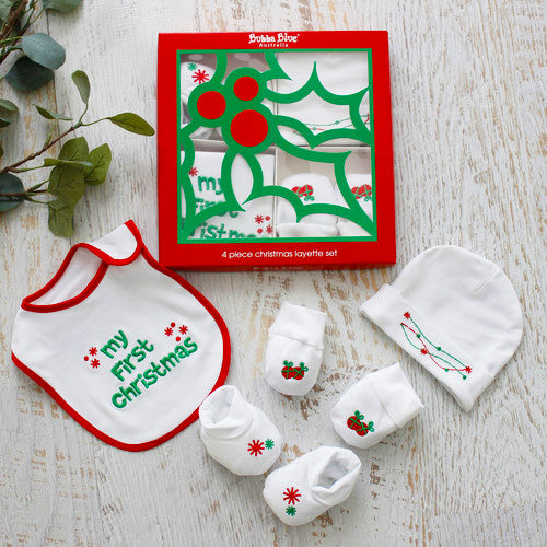 Baby Christmas layette set with bib, hat, and socks on a wooden surface.