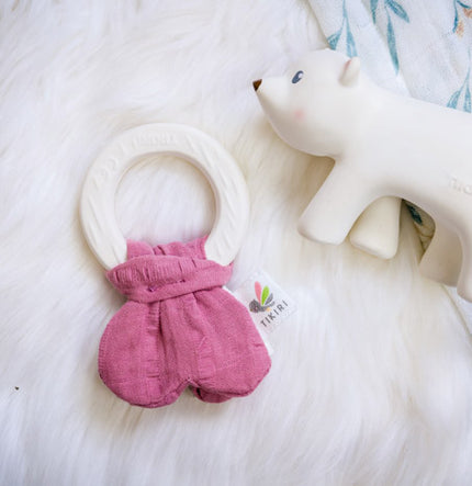 Pink baby toy with a white ring and a white bear toy on a white background