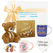 Collection of gifts including a teddy bear, Lindt Lindor chocolate box, mugs with personalized messages, and a gift bag from The Baby Gift Company.