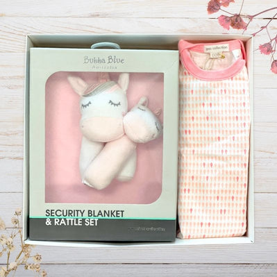 Baby security blanket and rattle box with unicorn design in packaging on a wooden surface.