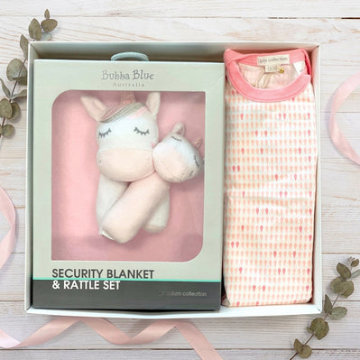 Baby security blanket and rattle box with unicorn design in packaging on a wooden surface.