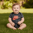 baby sitting outside on grass in nike outfit