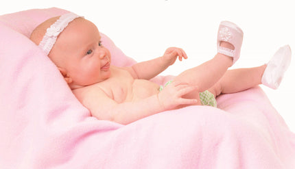 Baby lying on a pink blanket wearing a headband and socks