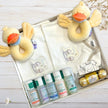 Baby gift set with plush duck toys, bottles, and other items on a wooden surface