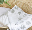 White blanket with gray elephant pattern on a woven surface