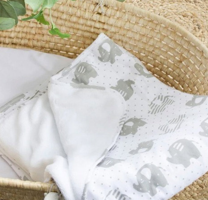 White blanket with gray elephant pattern on a woven surface