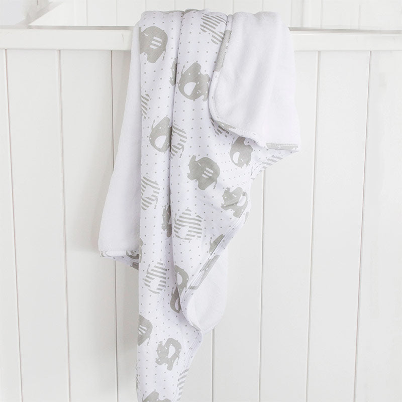 White blanket with gray pattern draped over a white wooden surface