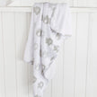 White blanket with gray pattern draped over a white wooden surface