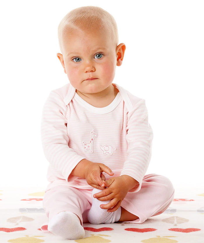 Baby in pink long sleeve cotton t-shirt sitting on a colorful blanket