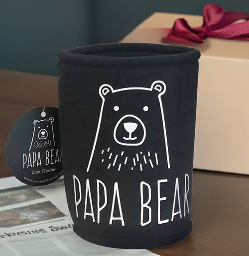 Black can cooler with 'Papa Bear' design on a table with a gift box in the background.