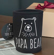Black can cooler with 'Papa Bear' design on a table with a gift box in the background.