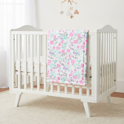 Peanutshell Pink Floral Cotton Baby Nursery Blanket placed on a cot.