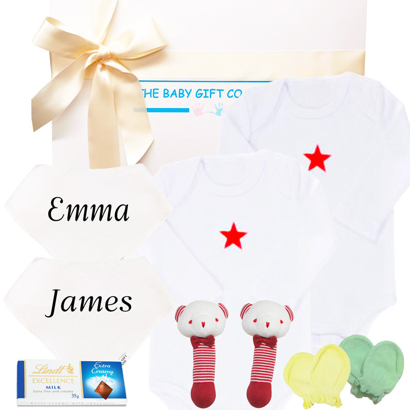 Baby gift set with white onesie, socks, and toys, branded 'The Baby Gift Company'.