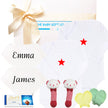 Baby gift set with white onesie, socks, and toys, branded 'The Baby Gift Company'.