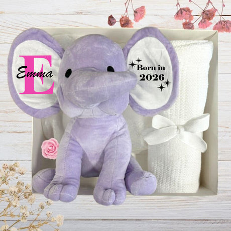 Purple Elephant toy with 'Emma' on ears, along with a white blanket in a gift box a wooden background