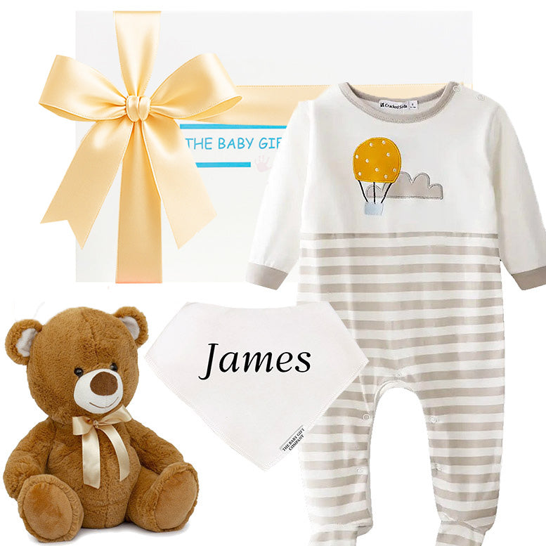 Baby gift set with striped onesie, teddy bear, and bib on a white background