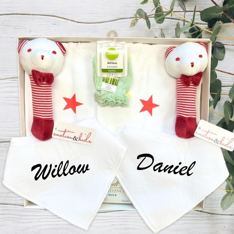Baby gift set with white onesies with red stars, custom name bibs, and red rattles in a baby gift box