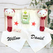 Baby gift set with white onesies with red stars, custom name bibs, and red rattles in a baby gift box