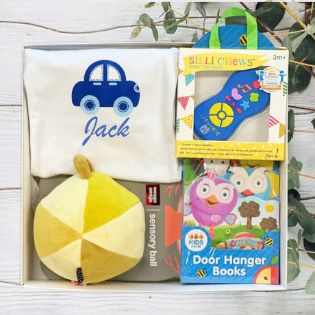 Collection of baby toys and books on a wooden surface with greenery in the background