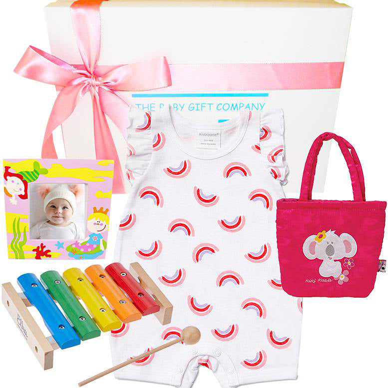 Baby gift set with baby romper, bag, photo album, xylophone, and toys on a white background.