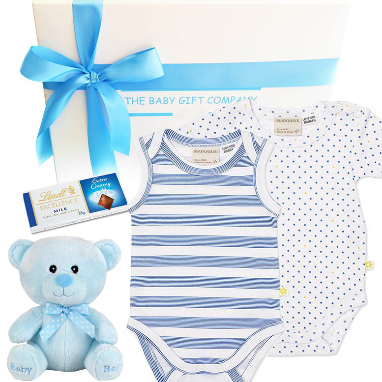 Baby gift set with striped onesie, teddy bear, and Lindt chocolate bar on a white background