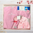 Baby gift set with pink 'Little Princess' shirt, hat, and toy in a gift box on a wooden surface.