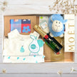 Collection of baby gift items including a moet bottle, lamb toy, and other products in a gift box