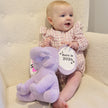 Baby sitting in chair with Purple Plush Elephant