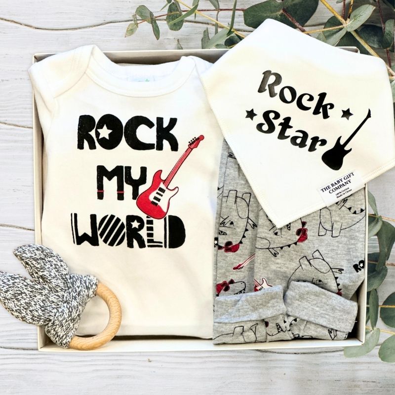 Baby clothing set with 'Rock My World' and 'Rock Star' text, baby bib, and teething ring in a gift box.